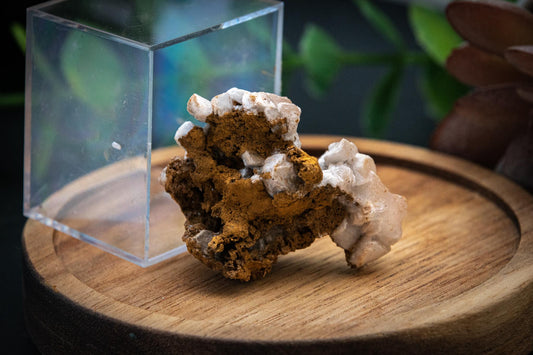 Rose petal Calcite on hematite specimen in display case